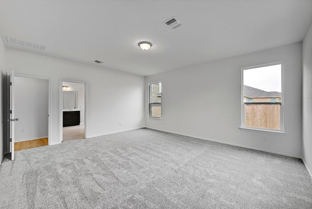 empty room with carpet, baseboards, and visible vents