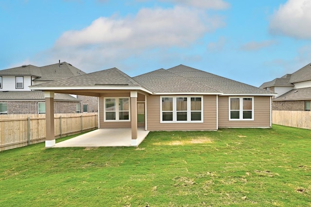 rear view of house featuring a shingled roof, a fenced backyard, a yard, and a patio area