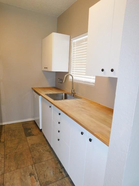 kitchen with dishwasher, white cabinetry, sink, and wood counters