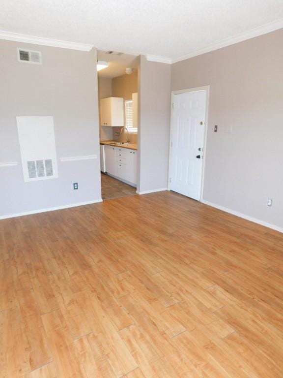 unfurnished living room with crown molding, sink, and light hardwood / wood-style floors