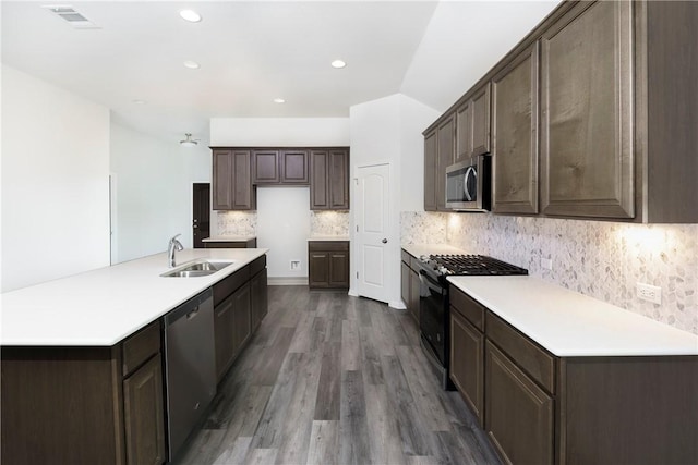 kitchen with sink, dark brown cabinets, stainless steel appliances, hardwood / wood-style floors, and decorative backsplash