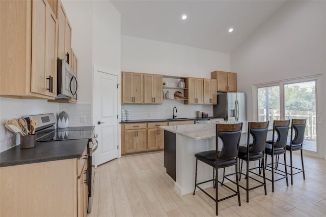 18208 Gregg Bluff Rd, Jonestown, TX 78645 - kitchen with high vaulted ceiling, appliances with stainless steel finishes, open shelves, a kitchen breakfast bar, and light wood-style floors