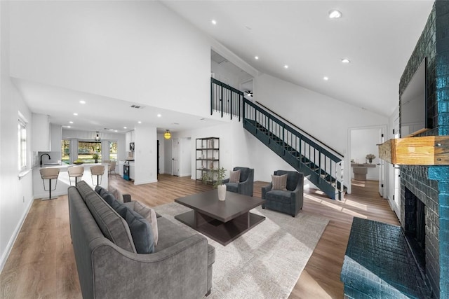 3507 Lovage Dr, Austin, TX 78727 - living room featuring a fireplace, stairs, light wood-type flooring, recessed lighting, and high vaulted ceiling