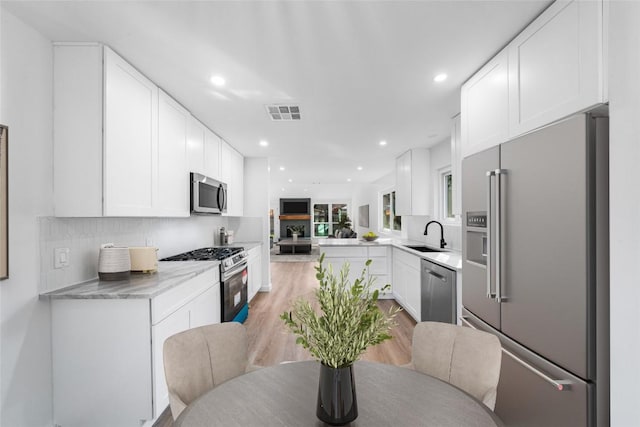 kitchen featuring stainless steel appliances, kitchen peninsula, and white cabinets