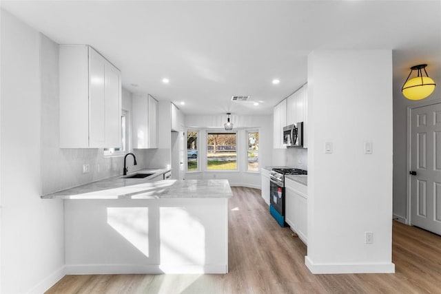 3507 Lovage Dr, Austin, TX 78727 - kitchen featuring stainless steel appliances, white cabinetry, a peninsula, light wood-style flooring, and recessed lighting