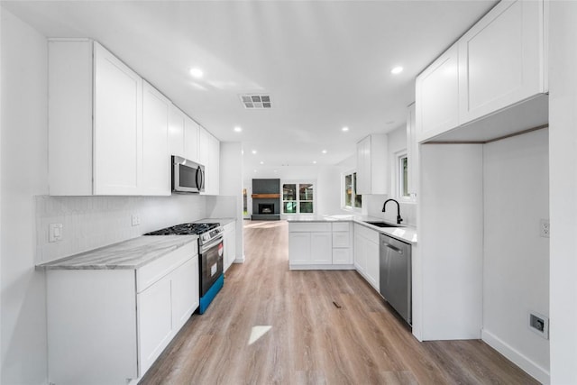 3507 Lovage Dr, Austin, TX 78727 - kitchen featuring appliances with stainless steel finishes, light wood-style flooring, recessed lighting, white cabinets, and backsplash