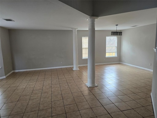 spare room with light tile patterned floors and decorative columns