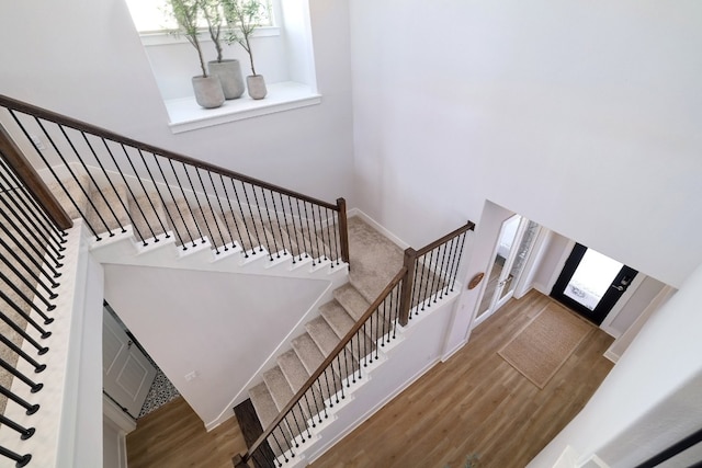 stairs featuring a high ceiling, baseboards, and wood finished floors