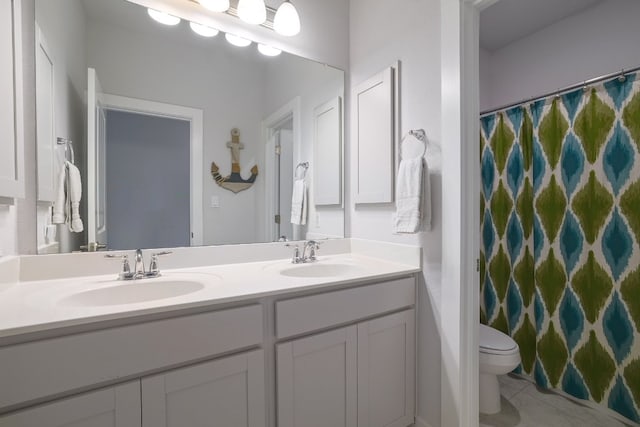 full bath featuring toilet, double vanity, a sink, and tile patterned floors