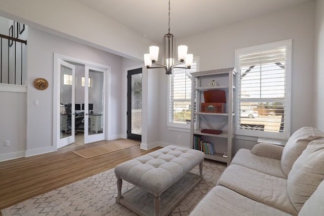 living area featuring light wood-type flooring, baseboards, and an inviting chandelier