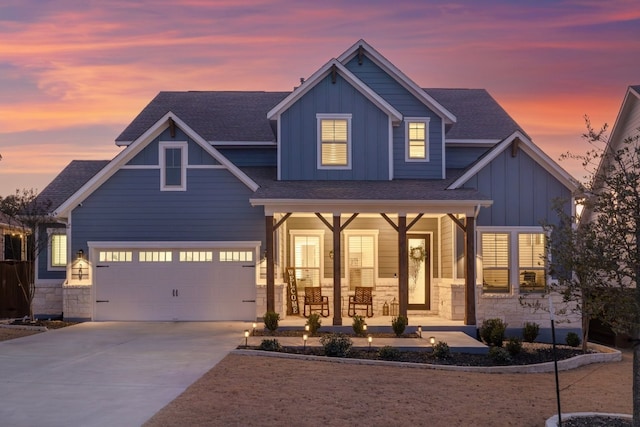 craftsman-style home featuring board and batten siding, covered porch, driveway, and stone siding