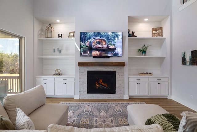 living room featuring a lit fireplace, baseboards, and wood finished floors