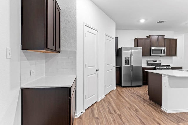 3201 Fresh Spring Rd, Pflugerville, TX 78660 - kitchen with appliances with stainless steel finishes, light wood-style floors, dark brown cabinetry, tasteful backsplash, and light countertops