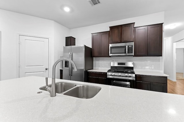 3201 Fresh Spring Rd, Pflugerville, TX 78660 - kitchen featuring appliances with stainless steel finishes, a sink, light countertops, dark brown cabinetry, and recessed lighting