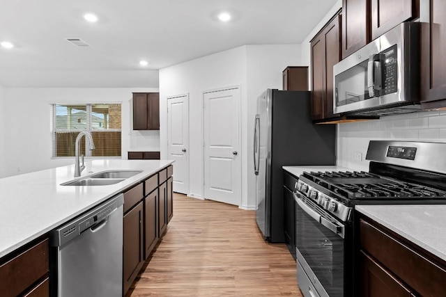 3201 Fresh Spring Rd, Pflugerville, TX 78660 - kitchen with appliances with stainless steel finishes, a sink, light wood-type flooring, dark brown cabinetry, and recessed lighting