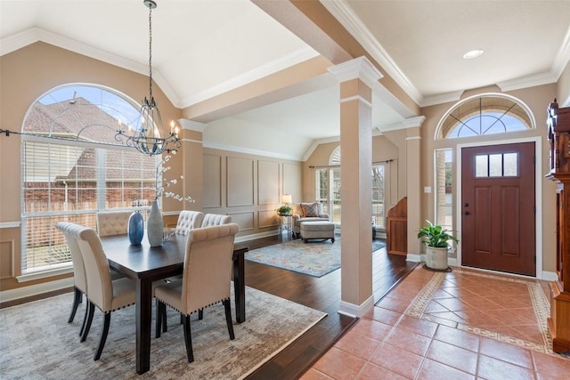 dining space featuring decorative columns, wood-type flooring, a wealth of natural light, and a chandelier