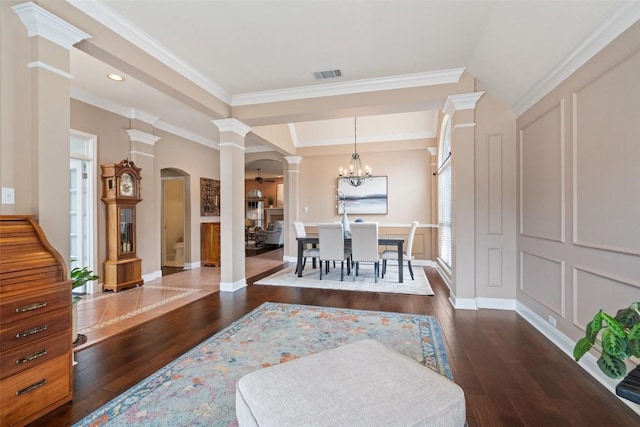 dining space featuring ornamental molding, a tray ceiling, dark hardwood / wood-style flooring, and ornate columns