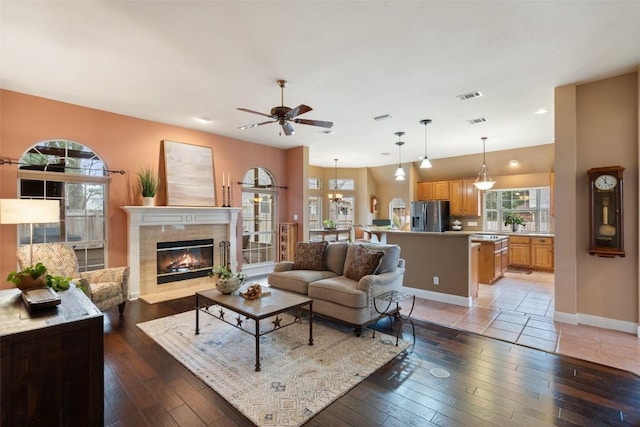 living room with a fireplace, a wealth of natural light, wood-type flooring, and ceiling fan