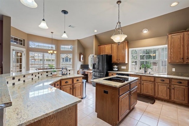 kitchen featuring a large island, sink, pendant lighting, black appliances, and light stone countertops