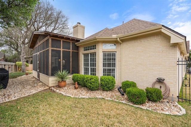 rear view of house with a yard and a sunroom