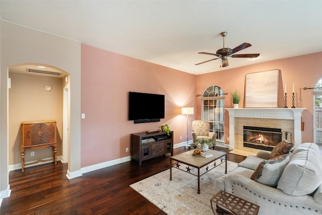 living room with a premium fireplace, ceiling fan, and dark hardwood / wood-style flooring