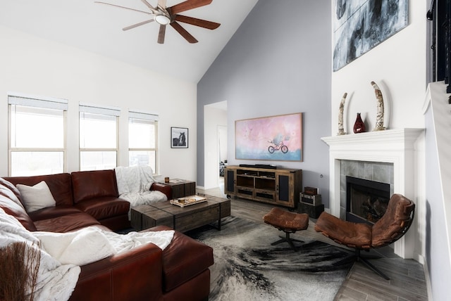 living room featuring a tiled fireplace, hardwood / wood-style flooring, high vaulted ceiling, and ceiling fan