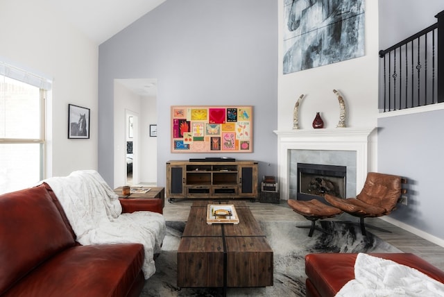 living room featuring a tiled fireplace, wood-type flooring, and high vaulted ceiling