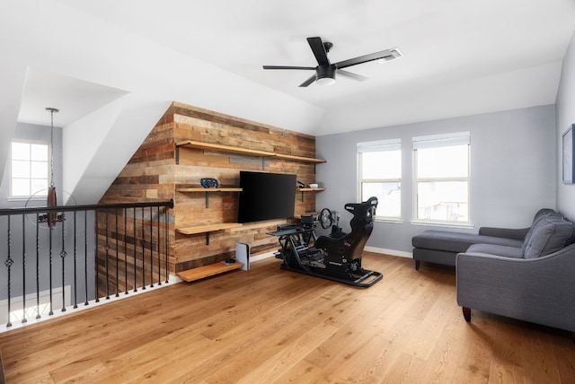 living room with vaulted ceiling, ceiling fan, and light wood-type flooring