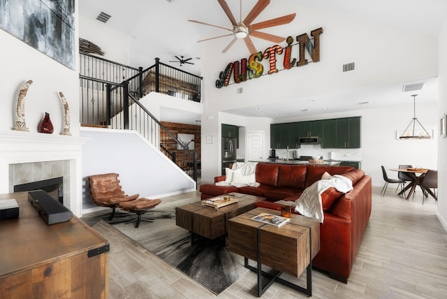 living room with light hardwood / wood-style floors, a tile fireplace, and ceiling fan