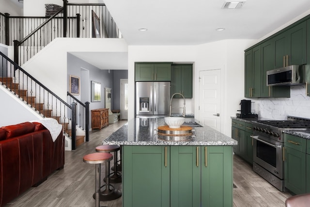 kitchen featuring light stone counters, a kitchen island, stainless steel appliances, and green cabinets