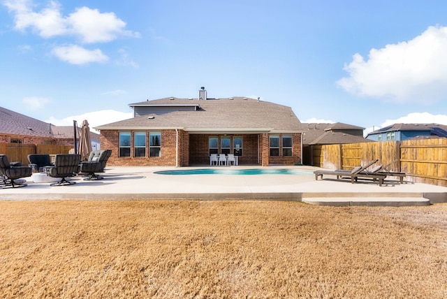 back of house featuring a fenced in pool, a yard, and a patio area