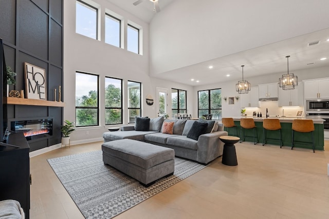 208 Tovas Secret Cv, Georgetown, TX 78628 - living room with recessed lighting, light wood finished floors, a fireplace, a towering ceiling, and a ceiling fan