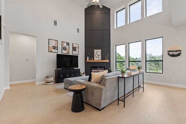 208 Tovas Secret Cv, Georgetown, TX 78628 - living room with a towering ceiling, plenty of natural light, a large fireplace, a ceiling fan, and light wood-type flooring
