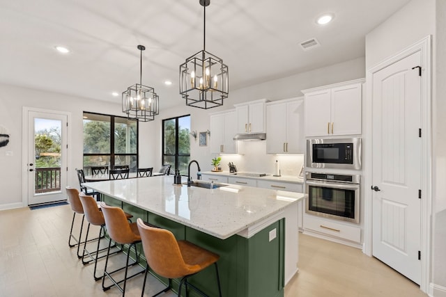 208 Tovas Secret Cv, Georgetown, TX 78628 - kitchen with stainless steel oven, built in microwave, under cabinet range hood, a chandelier, and white cabinetry