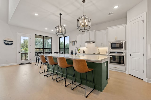 208 Tovas Secret Cv, Georgetown, TX 78628 - kitchen featuring oven, built in microwave, white cabinets, recessed lighting, and under cabinet range hood