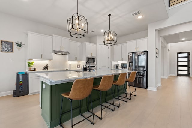 208 Tovas Secret Cv, Georgetown, TX 78628 - kitchen with stainless steel appliances, white cabinets, under cabinet range hood, a kitchen island with sink, and recessed lighting