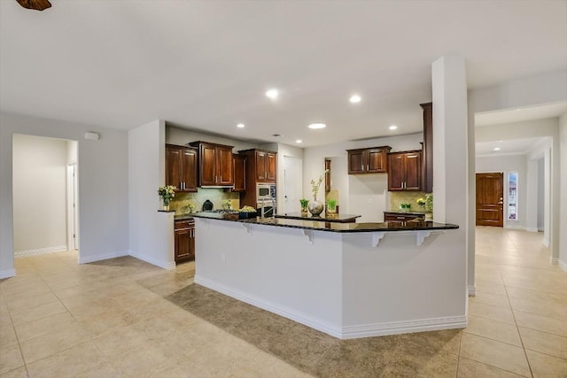 317 Yellow Rose Trl, Georgetown, TX 78633 - kitchen with decorative backsplash, recessed lighting, a breakfast bar, light tile patterned floors, and stainless steel microwave