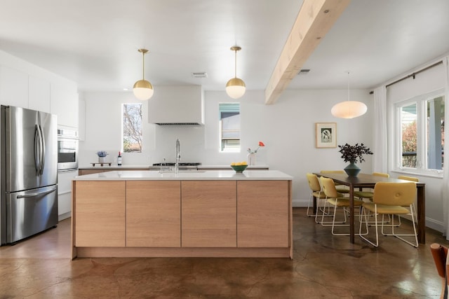 kitchen with appliances with stainless steel finishes, white cabinetry, hanging light fixtures, beam ceiling, and a center island with sink