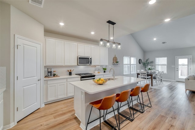 kitchen with sink, white cabinetry, a center island with sink, appliances with stainless steel finishes, and pendant lighting