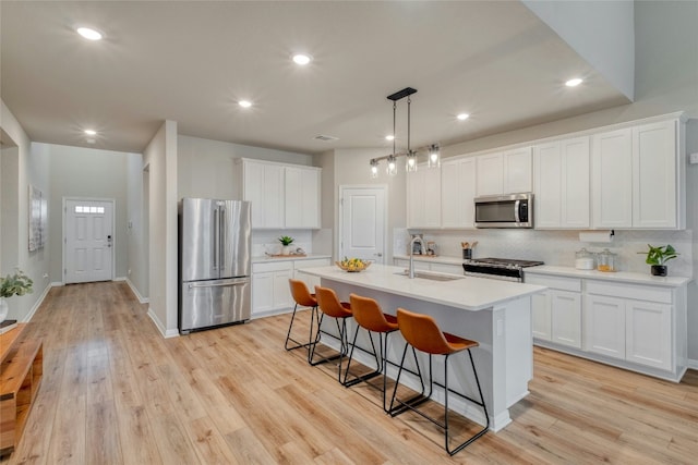 kitchen featuring sink, stainless steel appliances, white cabinets, and a center island with sink