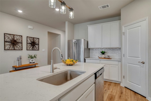 kitchen featuring sink, hanging light fixtures, appliances with stainless steel finishes, light hardwood / wood-style floors, and white cabinets