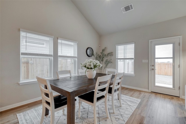 dining space featuring high vaulted ceiling and light hardwood / wood-style flooring