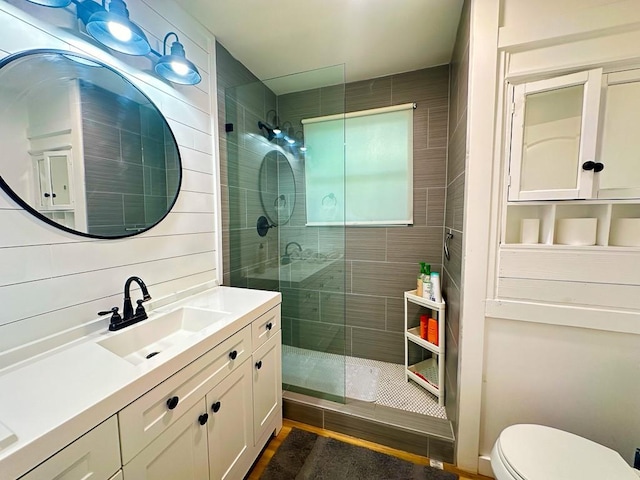 full bathroom with toilet, a tile shower, and vanity