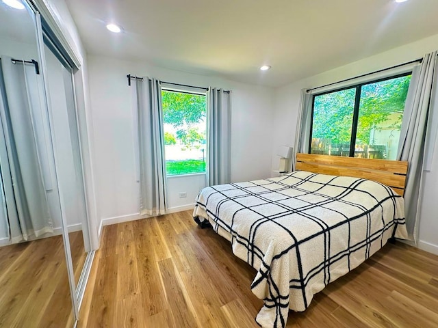 bedroom featuring light wood finished floors, a closet, recessed lighting, and baseboards