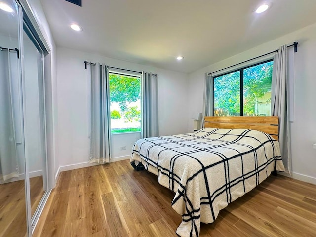 bedroom with baseboards, light wood finished floors, and recessed lighting