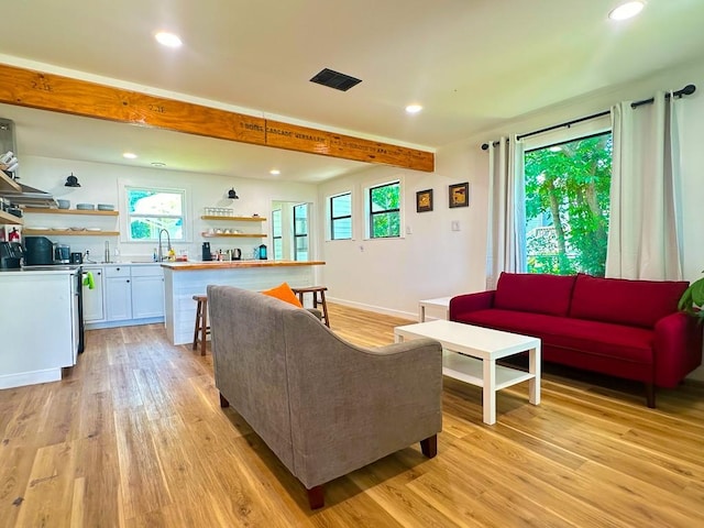 living area with light wood finished floors, visible vents, wet bar, beam ceiling, and recessed lighting