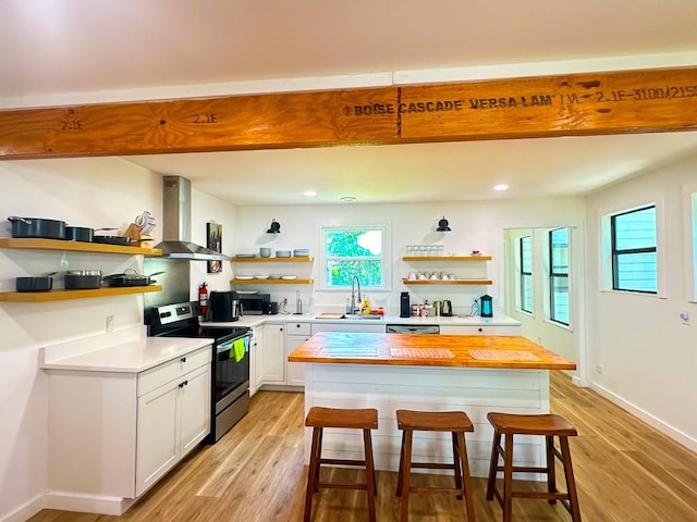 kitchen with a breakfast bar area, a sink, wall chimney exhaust hood, stainless steel electric stove, and open shelves