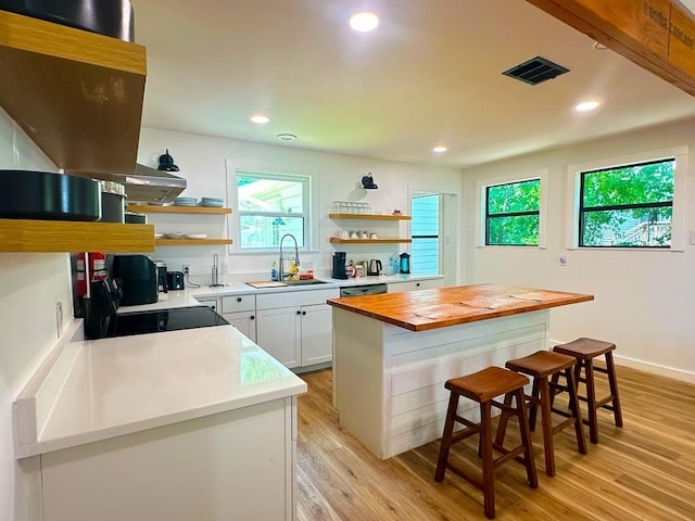 kitchen featuring butcher block countertops, open shelves, a sink, and a kitchen bar