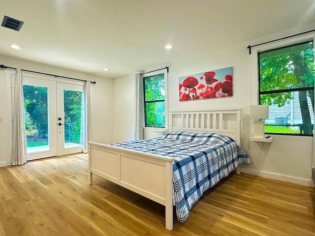 bedroom with access to outside, multiple windows, visible vents, and wood finished floors