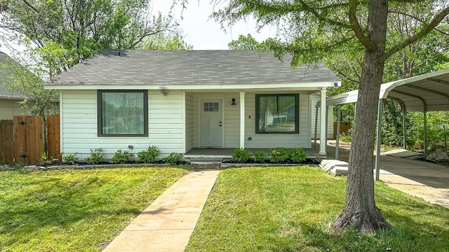 view of front of house with fence, roof with shingles, a front lawn, a porch, and a detached carport